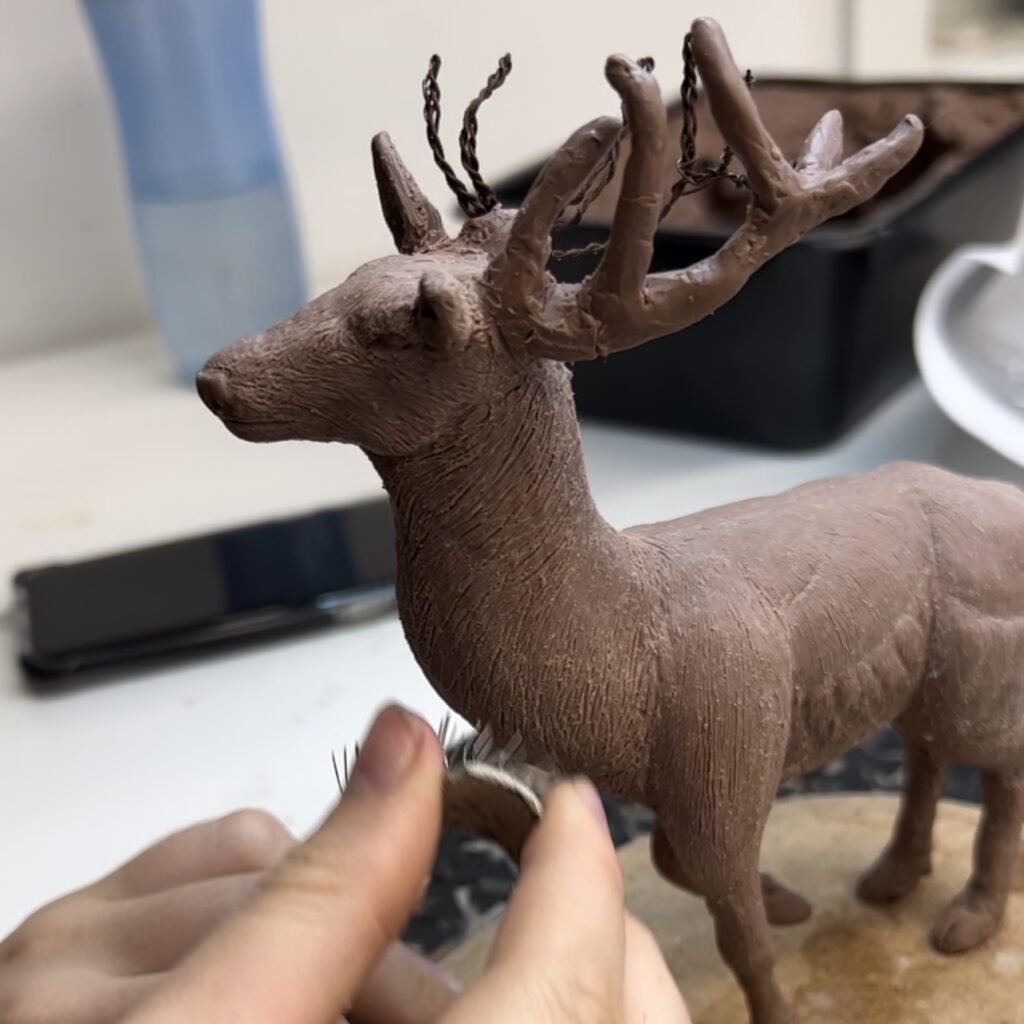 A photo showing a young girls hand sculpting a deer