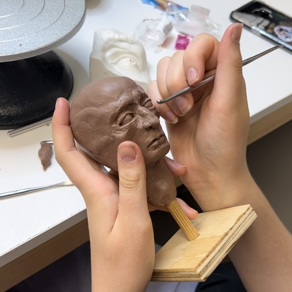 A young girl sculpting a mini head