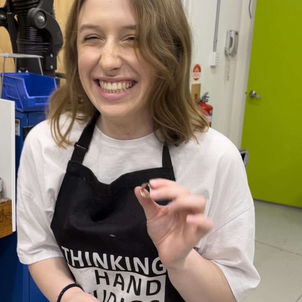 A young girl smiling and holding a silver ring